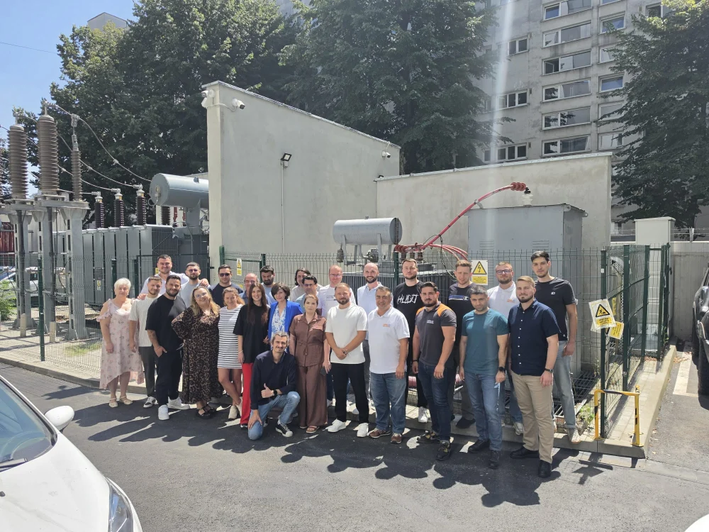 Fotografie de grup cu echipa, în fața instalațiilor electrice