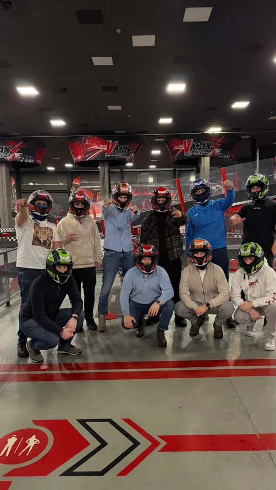 Colegii, cu căștile de protecție, pozând împreună la circuitul de karting